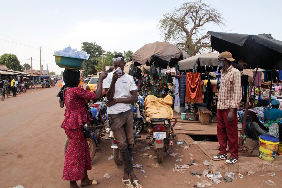 FILE - Amadou Coulibaly, a motorcycle taxi driver, drinks a sachet water to cool off under a blazing sun in Bamako, Mali, on April, 18, 2024. (AP Photo/Baba Ahmed, File)