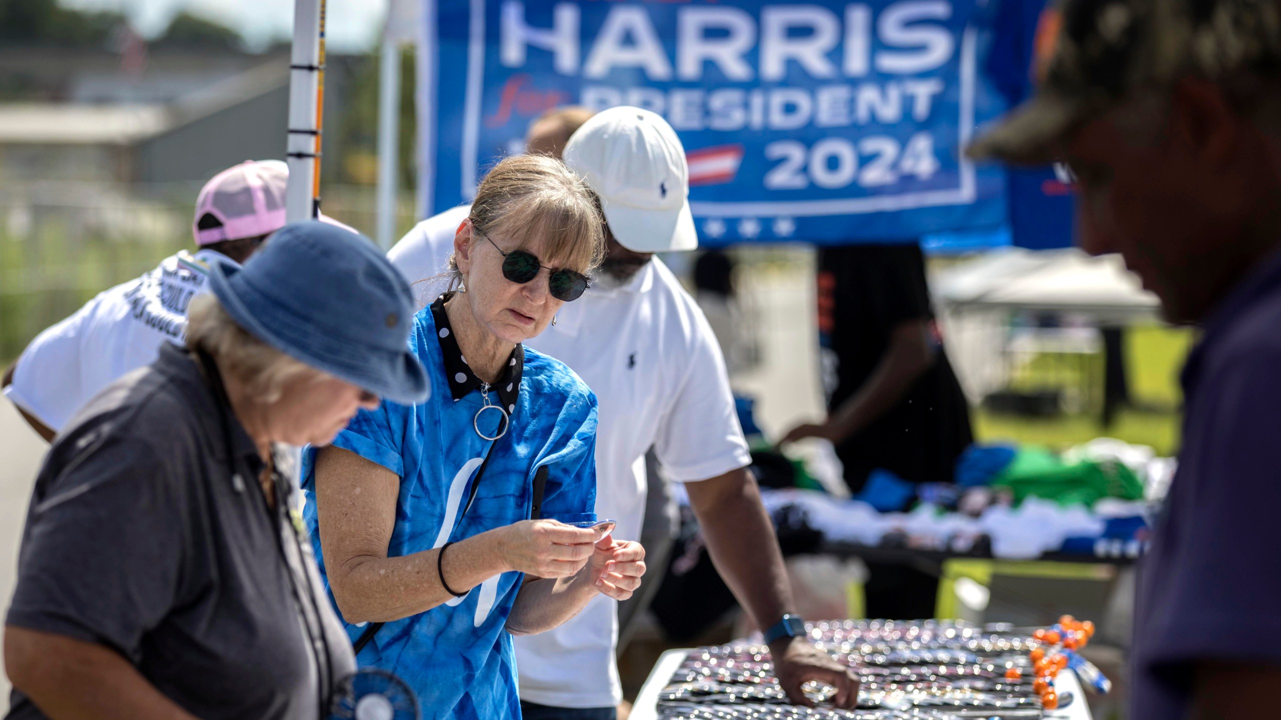 Cynthia Corey, from Brunswick, Ga., buys a Harris button from an vendor outside a venue where democratic presidential nominee Vice President Kamala Harris is planned to speak during a campaign event, Thursday, Aug. 29, 2024, in Savannah, Ga. (AP Photo/Stephen B. Morton)