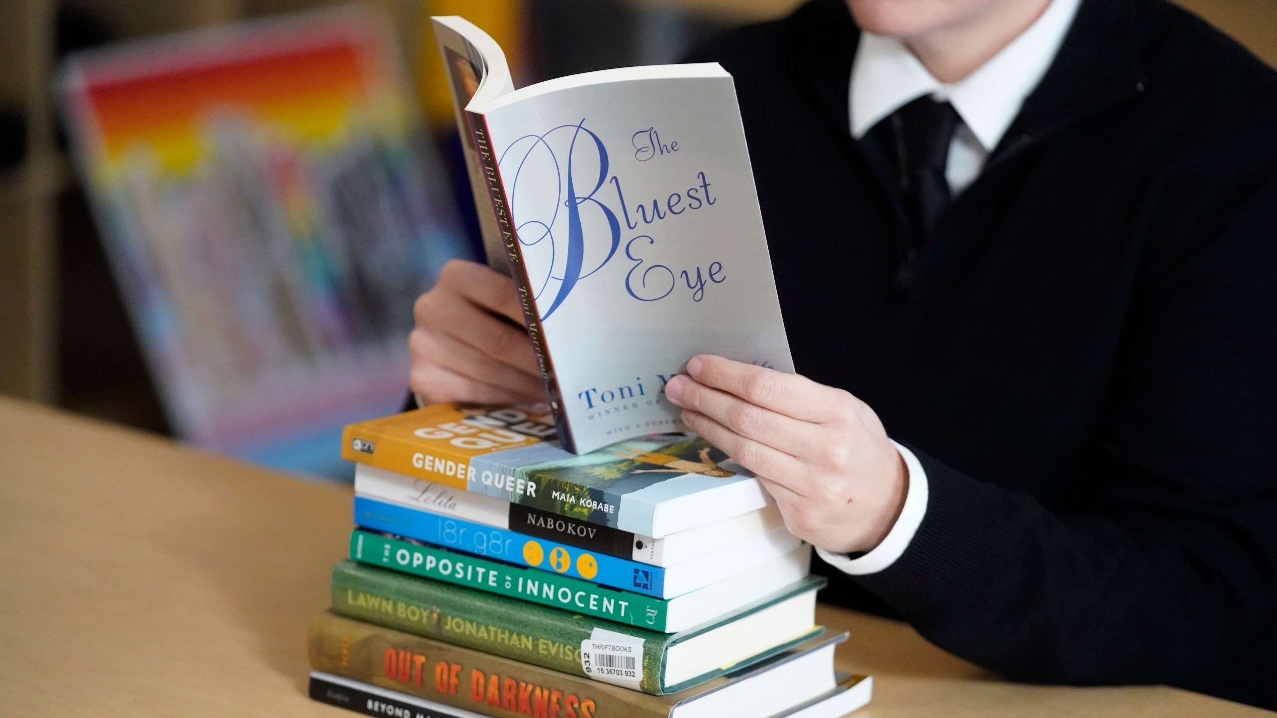 FILE - Amanda Darrow, director of youth, family and education programs at the Utah Pride Center, poses with books, including "The Bluest Eye," by Toni Morrison, that have been the subject of complaints from parents in Salt Lake City on Dec. 16, 2021. (AP Photo/Rick Bowmer, File)