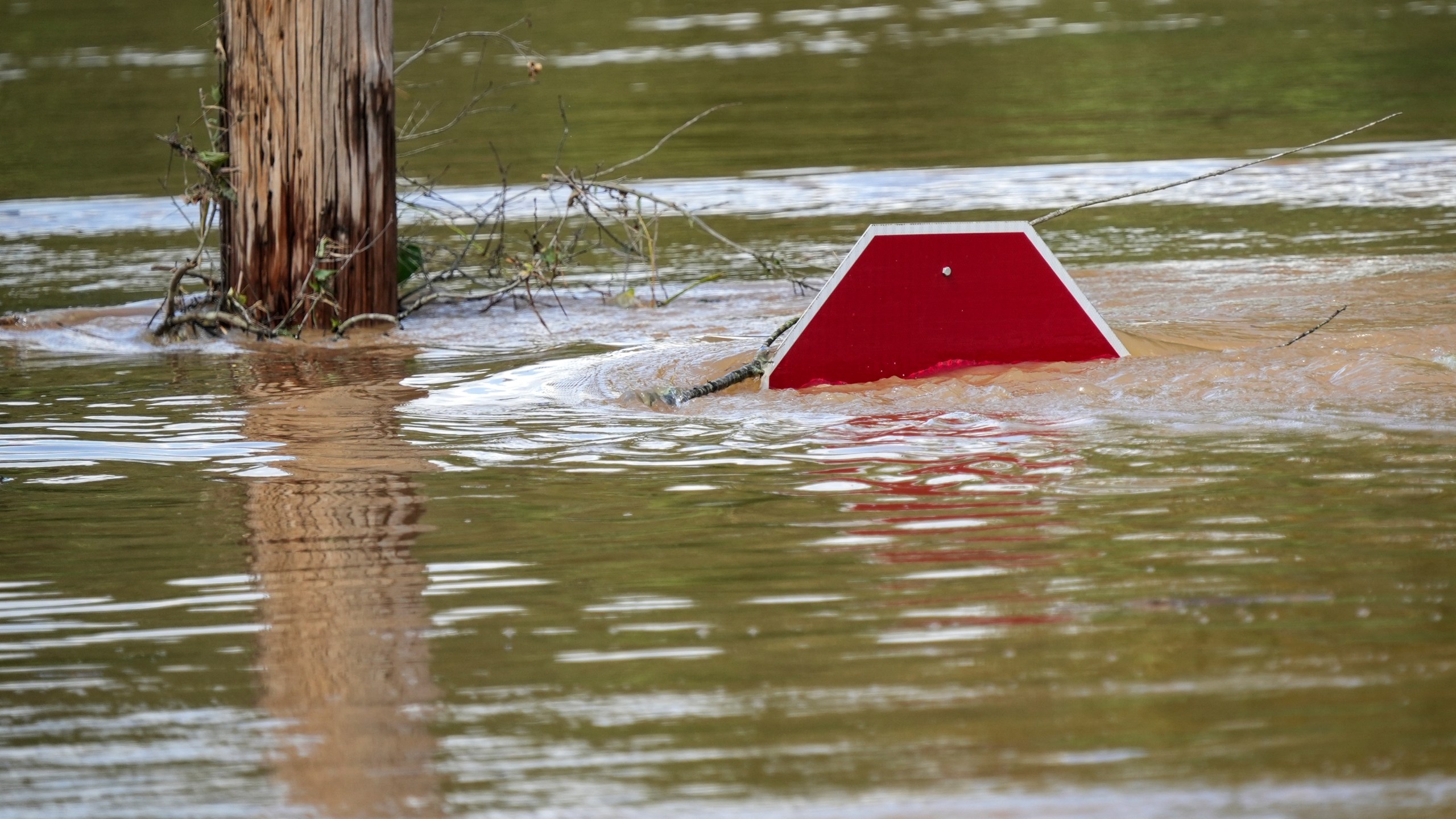 FILE - A stop sign is barely visible in floodwaters of a parking lot after torrential rain from Hurricane Helene, Saturday, Sept. 28, 2024, in Morganton, N.C. (AP Photo/Kathy Kmonicek, File)