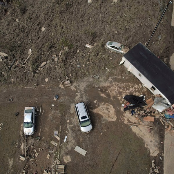 A destroyed mobile home and vehicles lay scattered across muddy land, Tuesday, Oct. 1, 2024, in Hendersonville, N.C., in the aftermath of Hurricane Helene. (AP Photo/Brittany Peterson)