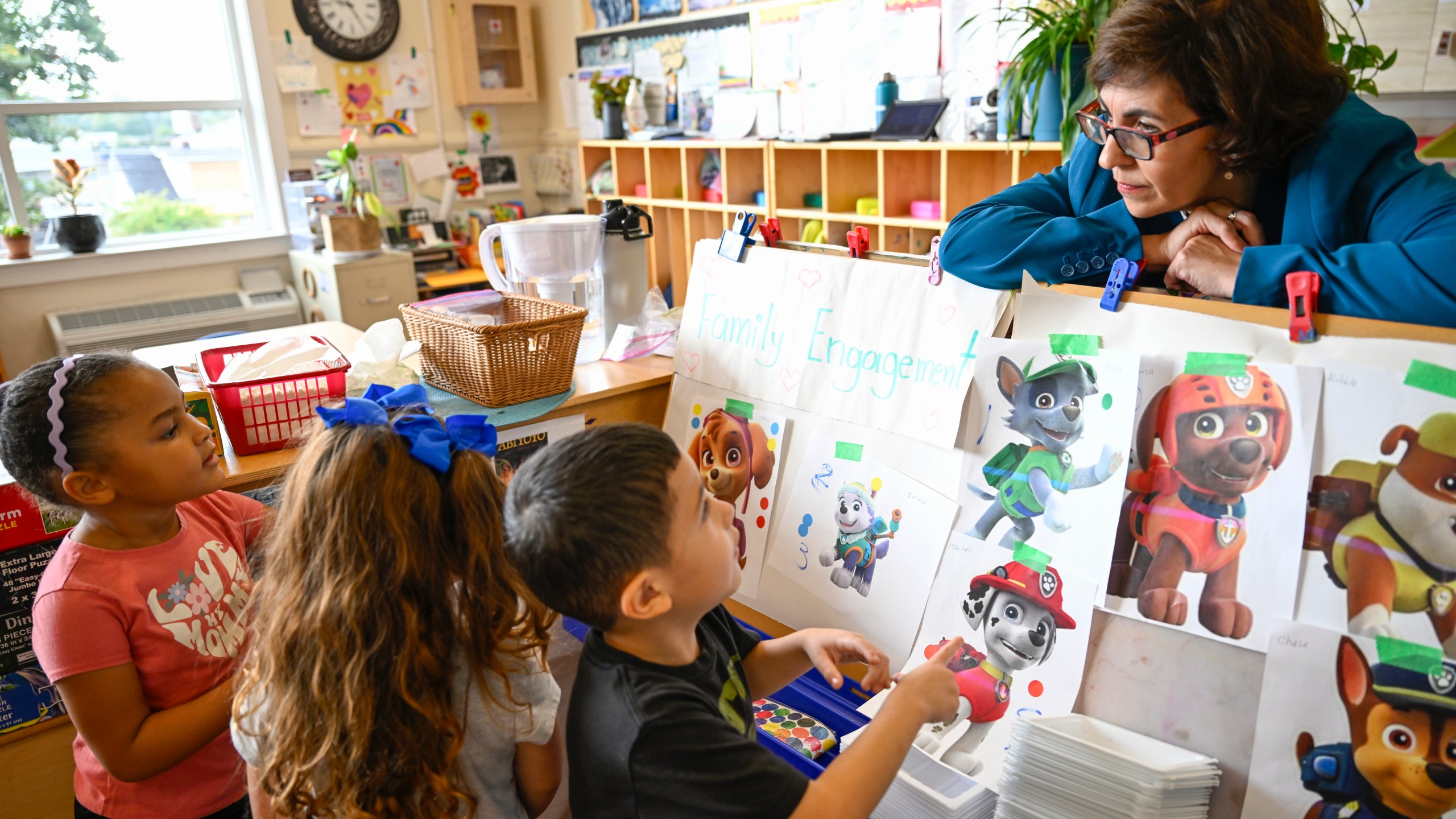 Preschool Executive Director Maria Isabel Ballivian, right, listens to her students on what characters of the TV show PAW Patrol they will vote for as their favorite character at the ACCA Child Development Center, Thursday, Sept. 19, 2024, in Annandale, Va. The students are getting foundational lessons on how to live in a democracy by allowing them to regularly vote on different things through out the day. (AP Photo/John McDonnell)