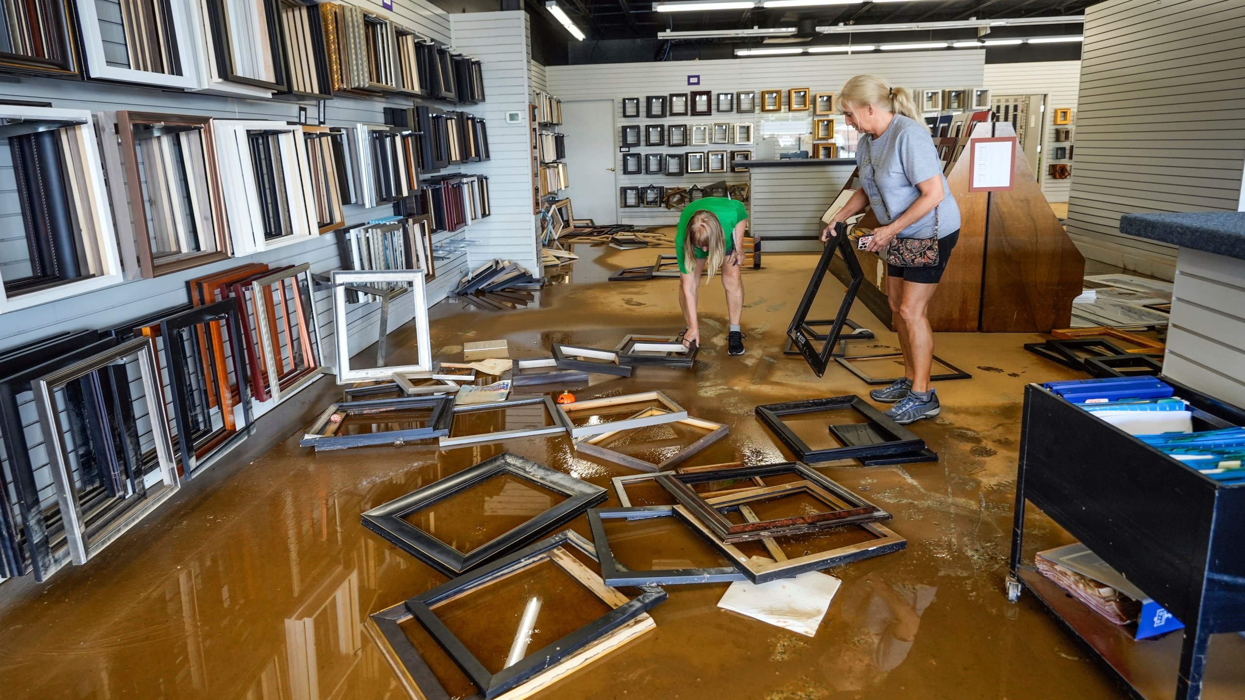 FILE - Employees Linda Bandy, left, and Carissa Sheehan clean up International Moulding frame shop damaged by floodwater from Hurricane Helene on North Green Street, Sept. 30, 2024, in Morganton, N.C. (AP Photo/Kathy Kmonicek, File)