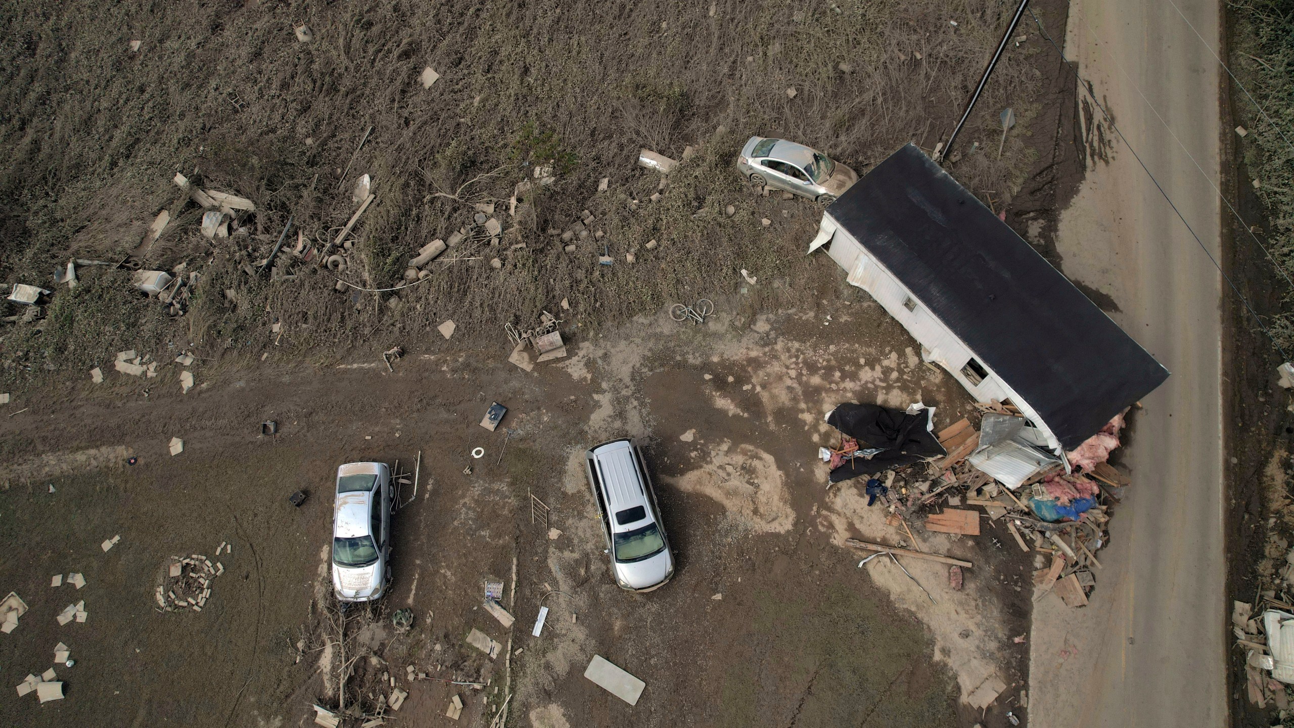 A destroyed mobile home and vehicles lay scattered across muddy land, Tuesday, Oct. 1, 2024, in Hendersonville, N.C., in the aftermath of Hurricane Helene. (AP Photo/Brittany Peterson)