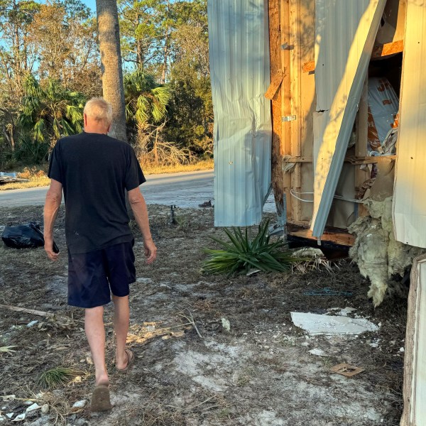 Dave Beamer walks past the partially destroyed trailer he's been living in, Sunday, Sept. 29, 2024, in Steinhatchee, Fla., after Hurricane Helene washed his home into a marsh. (AP Photo/Kate Payne)