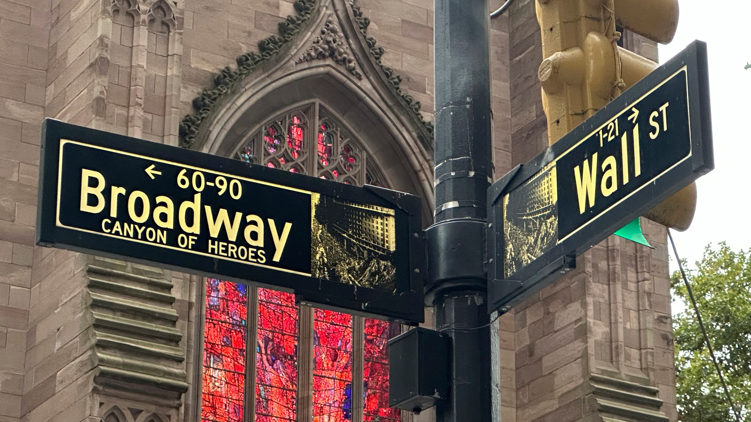 FILE - Signs mark the intersection of Broadway and Wall Street in the Financial District on Oct. 2, 2024, in New York. Trinity Church is in the background. (AP Photo/Peter Morgan, File)