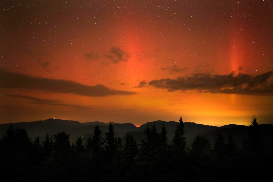 Flares of northern lights color the sky over the White Mountains just after midnight, Friday, Sept. 13, 2024, as viewed from a mountaintop in Chatham, N.H. Lights on the summit of Mount Washington can be seen on the ridgeline at left. (AP Photo/Robert F. Bukaty)