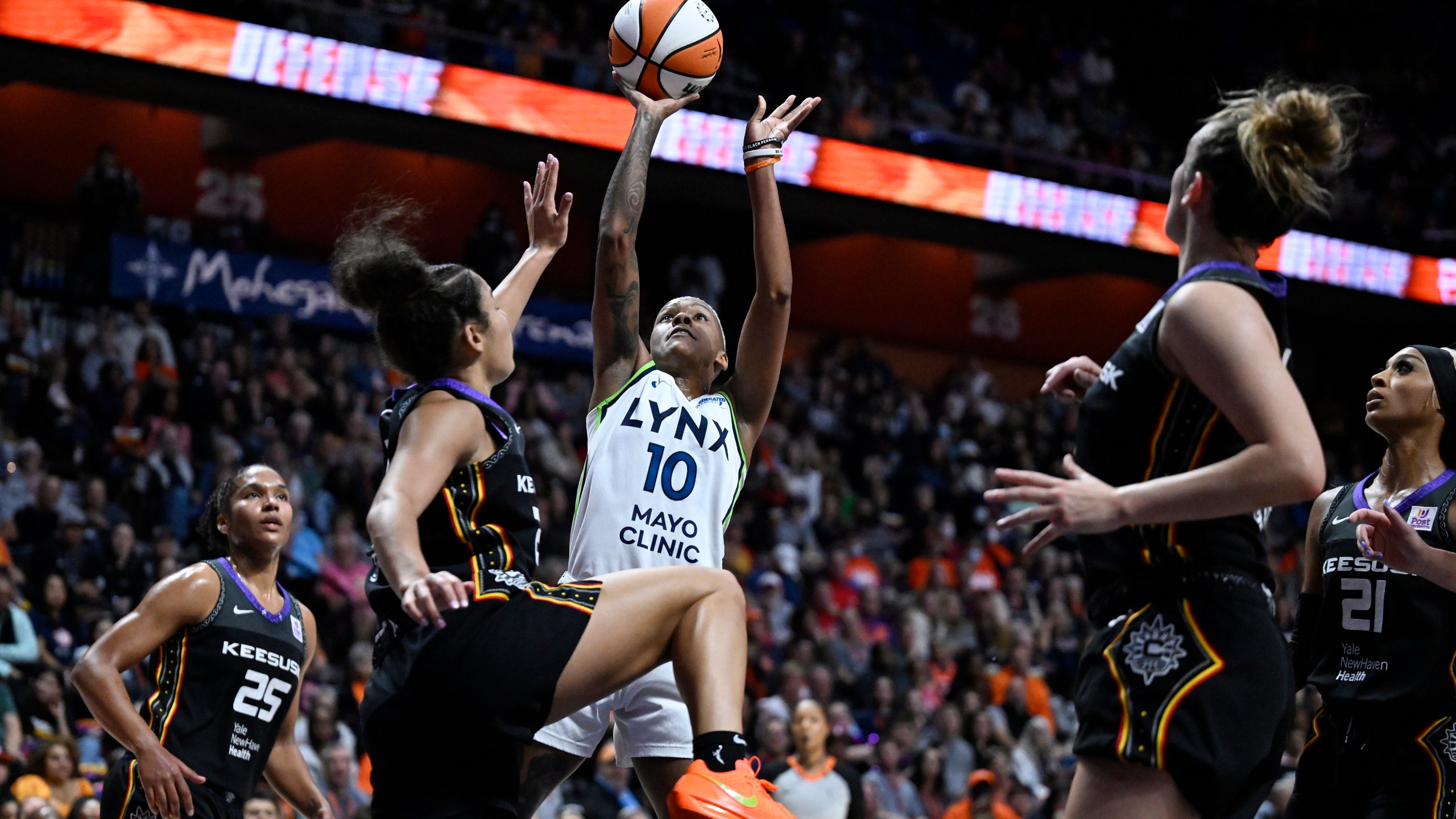 Minnesota Lynx guard Courtney Williams (10) shoots over Connecticut Sun guard Veronica Burton during the first half of a WNBA basketball semifinal game, Friday, Oct. 4, 2024, in Uncasville, Conn. (AP Photo/Jessica Hill)