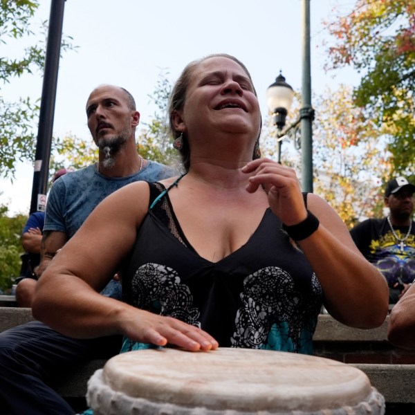 A woman plays music at a drum circle Friday, Oct. 4, 2024 in Asheville, N.C., a week after Hurricane Helene upended lives across the Southeast. (AP Photo/Brittany Peterson)