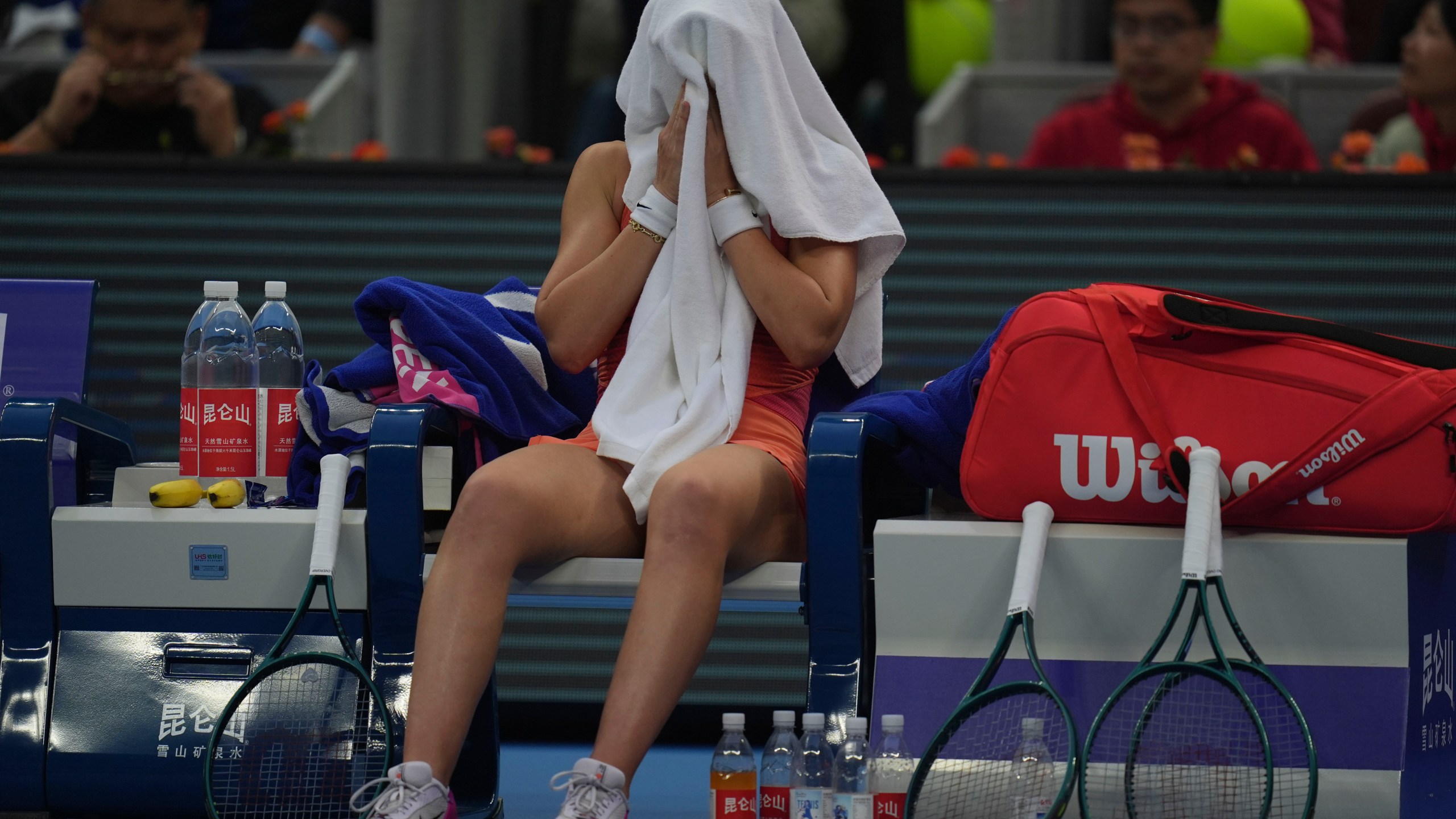 Paula Badosa of Spain cover herself with a towel during sets against Coco Gauff of the United States in a women's singles semi-final match for the China Open tennis tournament held at the National Tennis Center in Beijing, Saturday, Oct. 5, 2024. (AP Photo/Ng Han Guan)