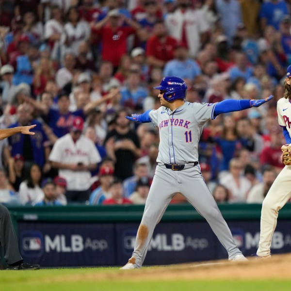 New York Mets' Jose Iglesias reacts past Philadelphia Phillies third base Alec Bohm after making it safely to third on a run scoring single by New York Mets' J.D. Martinez during the eighth inning of Game 1 of a baseball NL Division Series, Saturday, Oct. 5, 2024, in Philadelphia. (AP Photo/Matt Slocum)