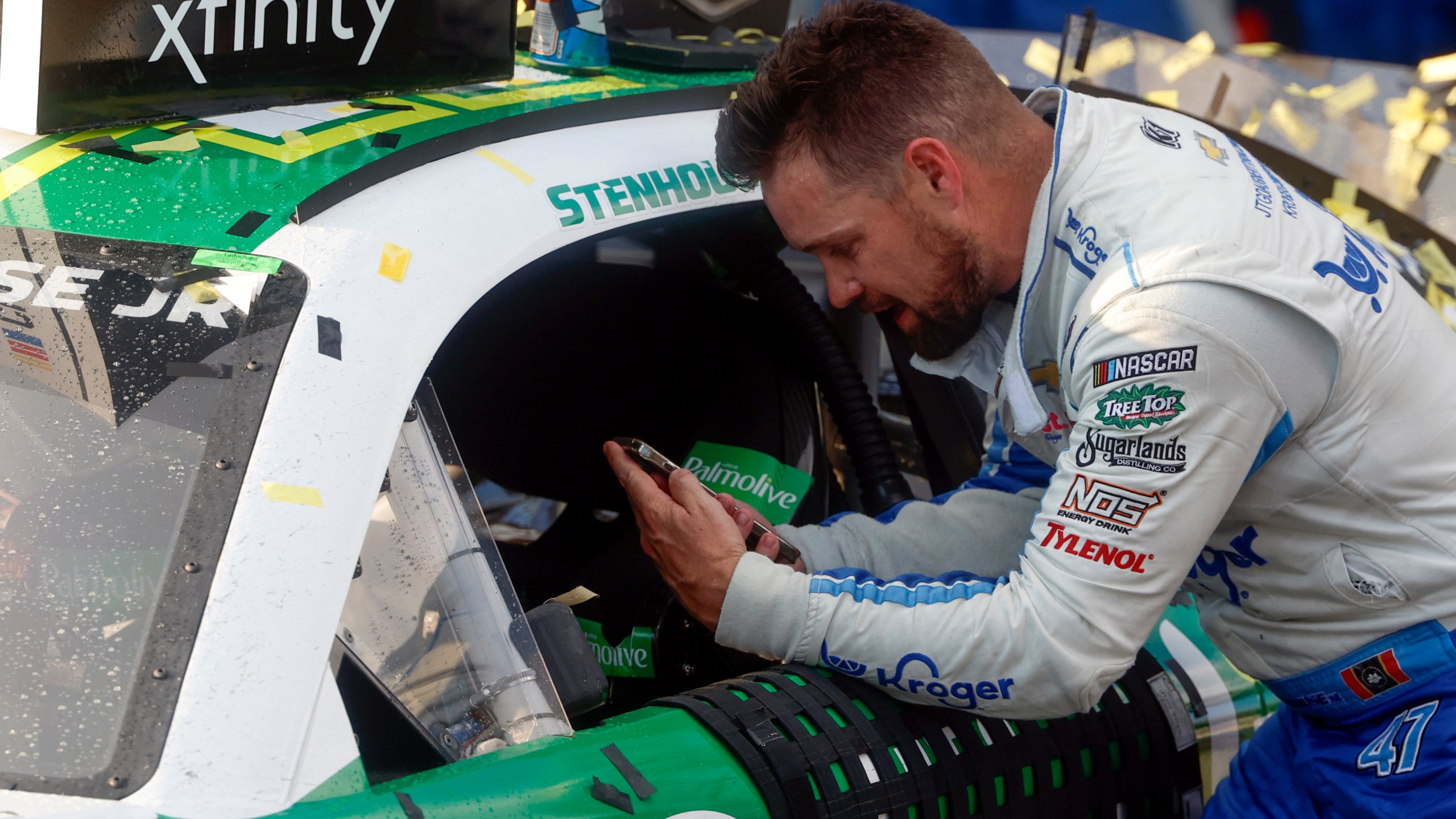 Driver Ricky Stenhouse Jr. talks with his wife and son on the phone as he celebrates in Victory Lane after a NASCAR Cup Series auto race at Talladega Superspeedway, Sunday, Oct. 6, 2024, in Talladega, Ala. (AP Photo/ Butch Dill)