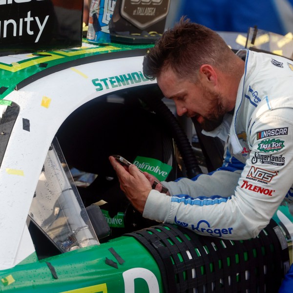 Driver Ricky Stenhouse Jr. talks with his wife and son on the phone as he celebrates in Victory Lane after a NASCAR Cup Series auto race at Talladega Superspeedway, Sunday, Oct. 6, 2024, in Talladega, Ala. (AP Photo/ Butch Dill)