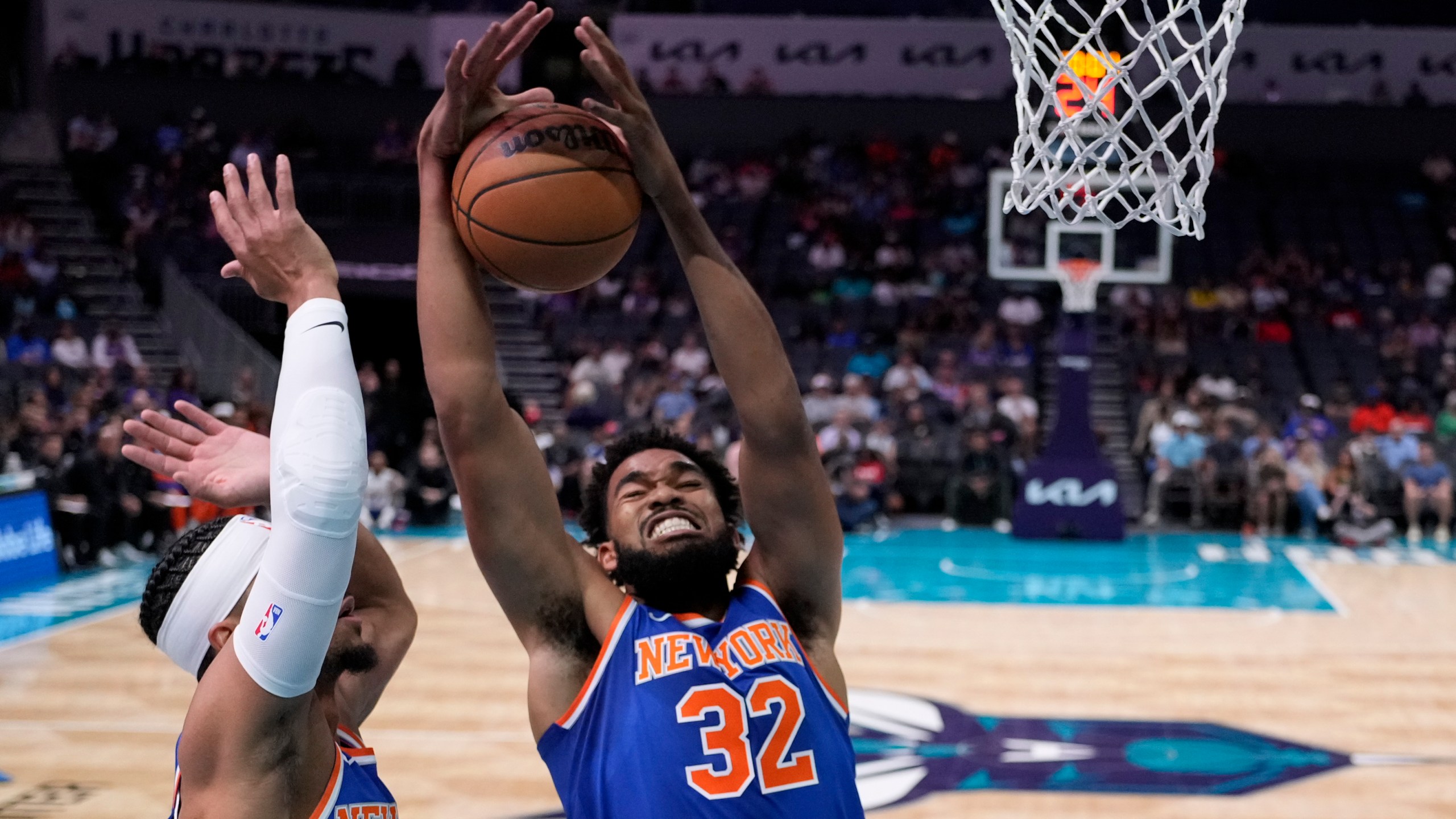 New York Knicks center Karl-Anthony Towns pulls down a rebound as guard Josh Hart looks on during the first half of a preseason NBA basketball game against the Charlotte Hornets, Sunday, Oct. 6, 2024, in Charlotte, N.C. (AP Photo/Chris Carlson)