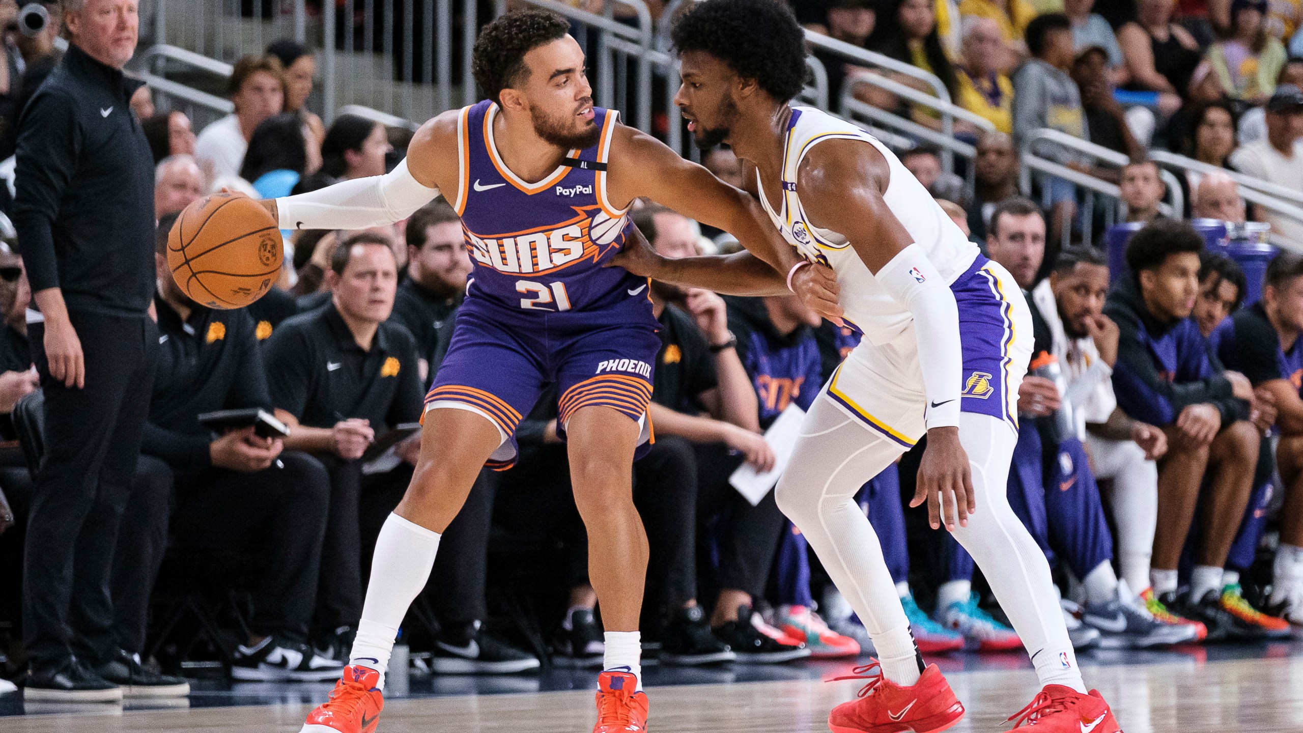 Phoenix Suns guard Tyus Jones (21) dribbles under pressure from Los Angeles Lakers guard Bronny James (9) during the first half of a preseason NBA basketball game Sunday, Oct. 6, 2024, in Palm Desert, Calif. (AP Photo/William Liang)