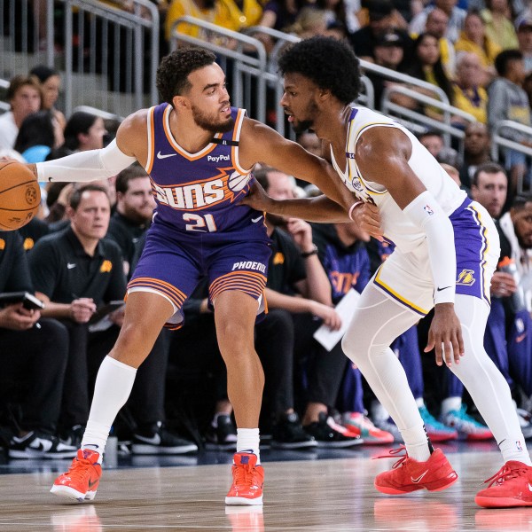 Phoenix Suns guard Tyus Jones (21) dribbles under pressure from Los Angeles Lakers guard Bronny James (9) during the first half of a preseason NBA basketball game Sunday, Oct. 6, 2024, in Palm Desert, Calif. (AP Photo/William Liang)