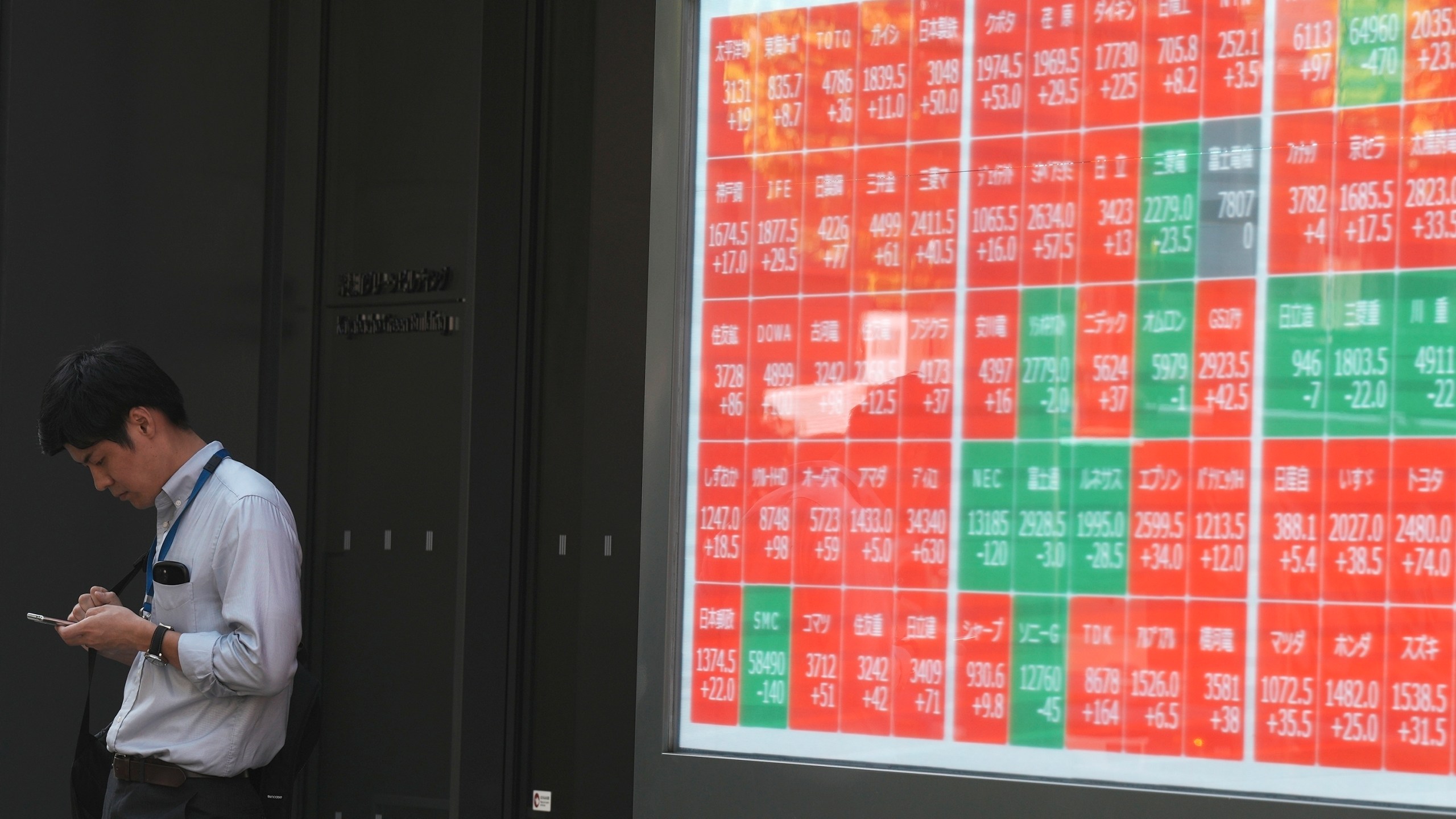 FILE - A person stands near an electronic stock board showing Japan's Nikkei index at a securities firm Wednesday, Sept. 18, 2024, in Tokyo. (AP Photo/Eugene Hoshiko, File)