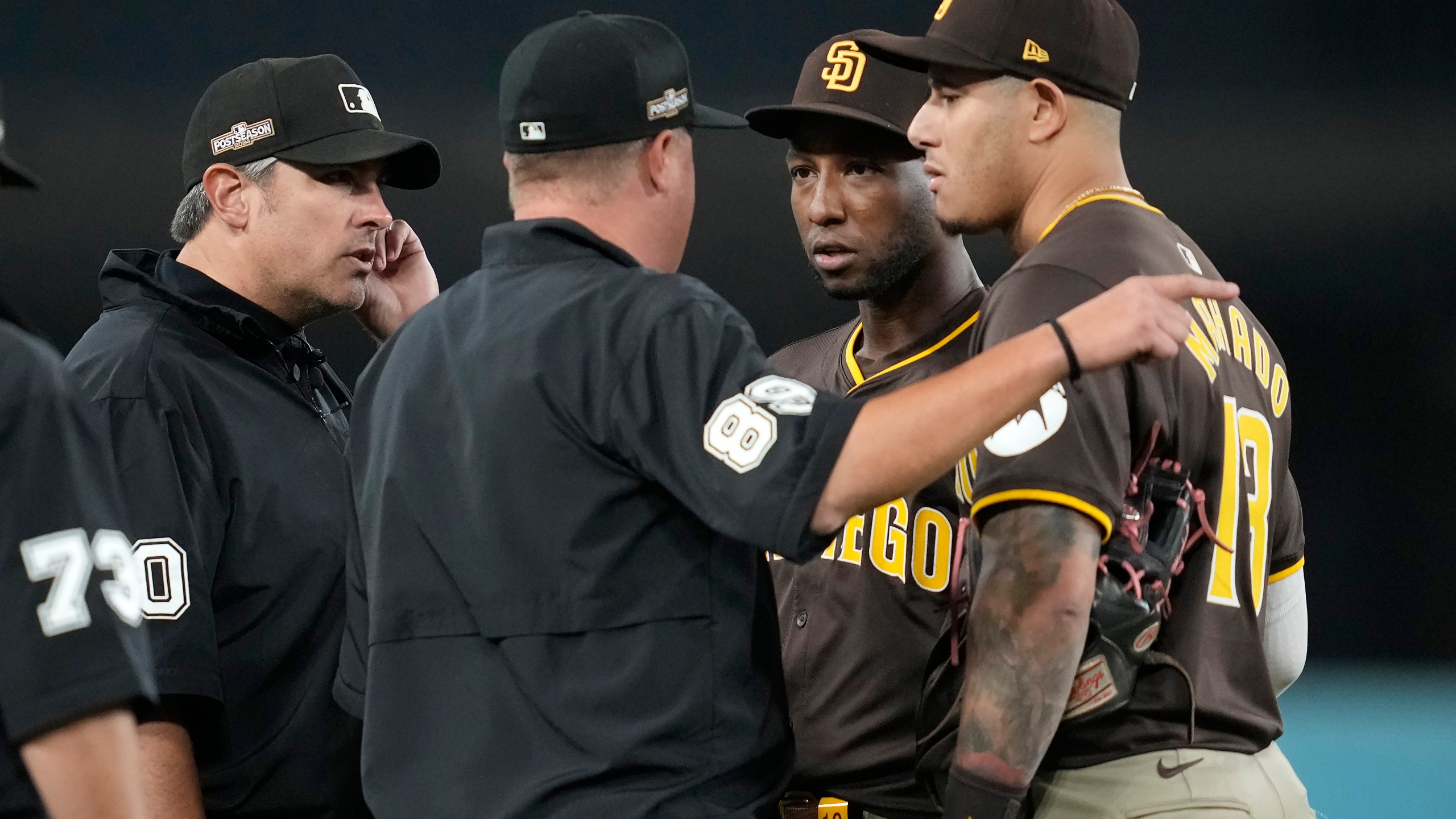 San Diego Padres left fielder Jurickson Profar, second from right, and third baseman Manny Machado talk to the umpires after items were thrown at Profar in the outfield during the seventh inning in Game 2 of a baseball NL Division Series against the Los Angeles Dodgers, Sunday, Oct. 6, 2024, in Los Angeles. (AP Photo/Ashley Landis)