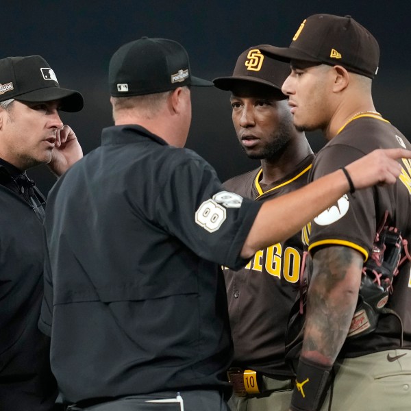 San Diego Padres left fielder Jurickson Profar, second from right, and third baseman Manny Machado talk to the umpires after items were thrown at Profar in the outfield during the seventh inning in Game 2 of a baseball NL Division Series against the Los Angeles Dodgers, Sunday, Oct. 6, 2024, in Los Angeles. (AP Photo/Ashley Landis)