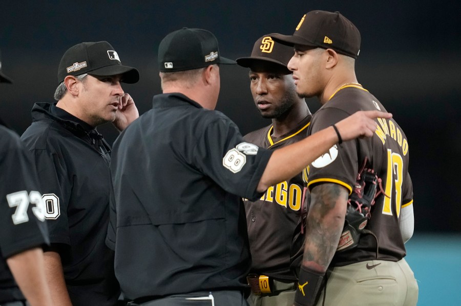 San Diego Padres left fielder Jurickson Profar, second from right, and third baseman Manny Machado talk to the umpires after items were thrown at Profar in the outfield during the seventh inning in Game 2 of a baseball NL Division Series against the Los Angeles Dodgers, Sunday, Oct. 6, 2024, in Los Angeles. (AP Photo/Ashley Landis)