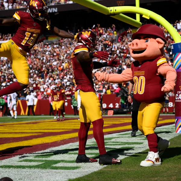 FILE - Washington Commanders running back Brian Robinson Jr., second from right, celebrates his touchdown with mascot Major Tuddy, right, during the first half of an NFL football game against the Cleveland Browns, Sunday, Oct. 6, 2024, in Landover, Md. Also seen is Commanders wide receiver Olamide Zaccheaus (14). (AP Photo/Nick Wass, File)