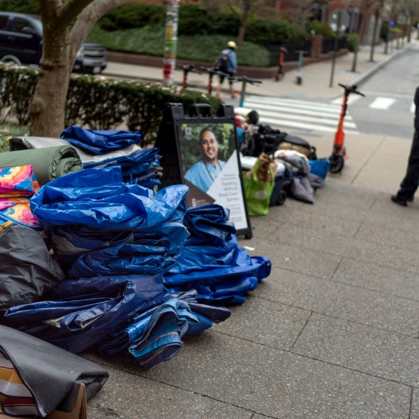 FILE - Tarps, sleeping bags and blankets sit piled on a sidewalk after an encampment protesting the Israel-Hamas war was taken down at Brown University as a campus security officer stands by, Tuesday, April 30, 2024, in Providence, R.I. (AP Photo/David Goldman, File)