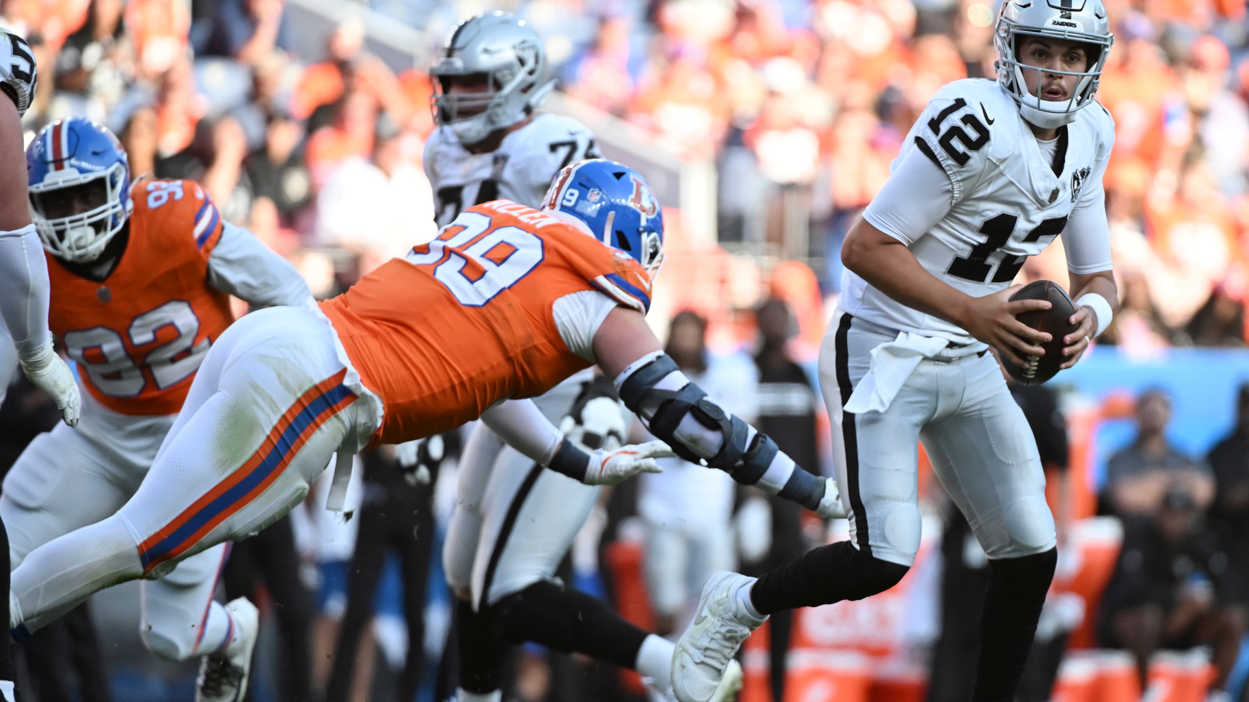 Las Vegas Raiders quarterback Aidan O'Connell, right, avoids Denver Broncos defensive end Zach Allen in the second half of an NFL football gam,e Sunday, Oct. 6, 2024, in Denver. (AP Photo/Geneva Heffernan)