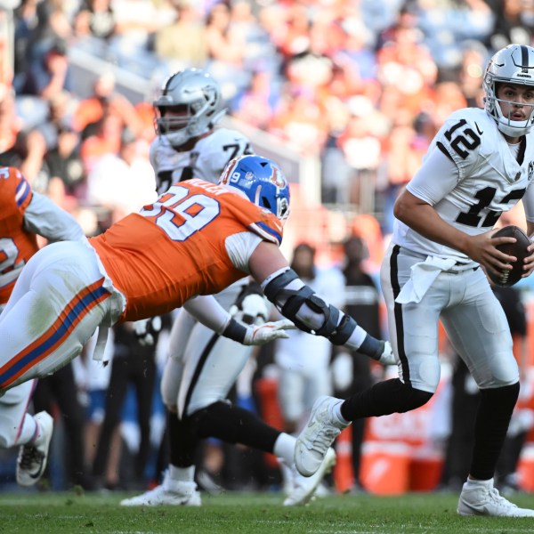 Las Vegas Raiders quarterback Aidan O'Connell, right, avoids Denver Broncos defensive end Zach Allen in the second half of an NFL football gam,e Sunday, Oct. 6, 2024, in Denver. (AP Photo/Geneva Heffernan)