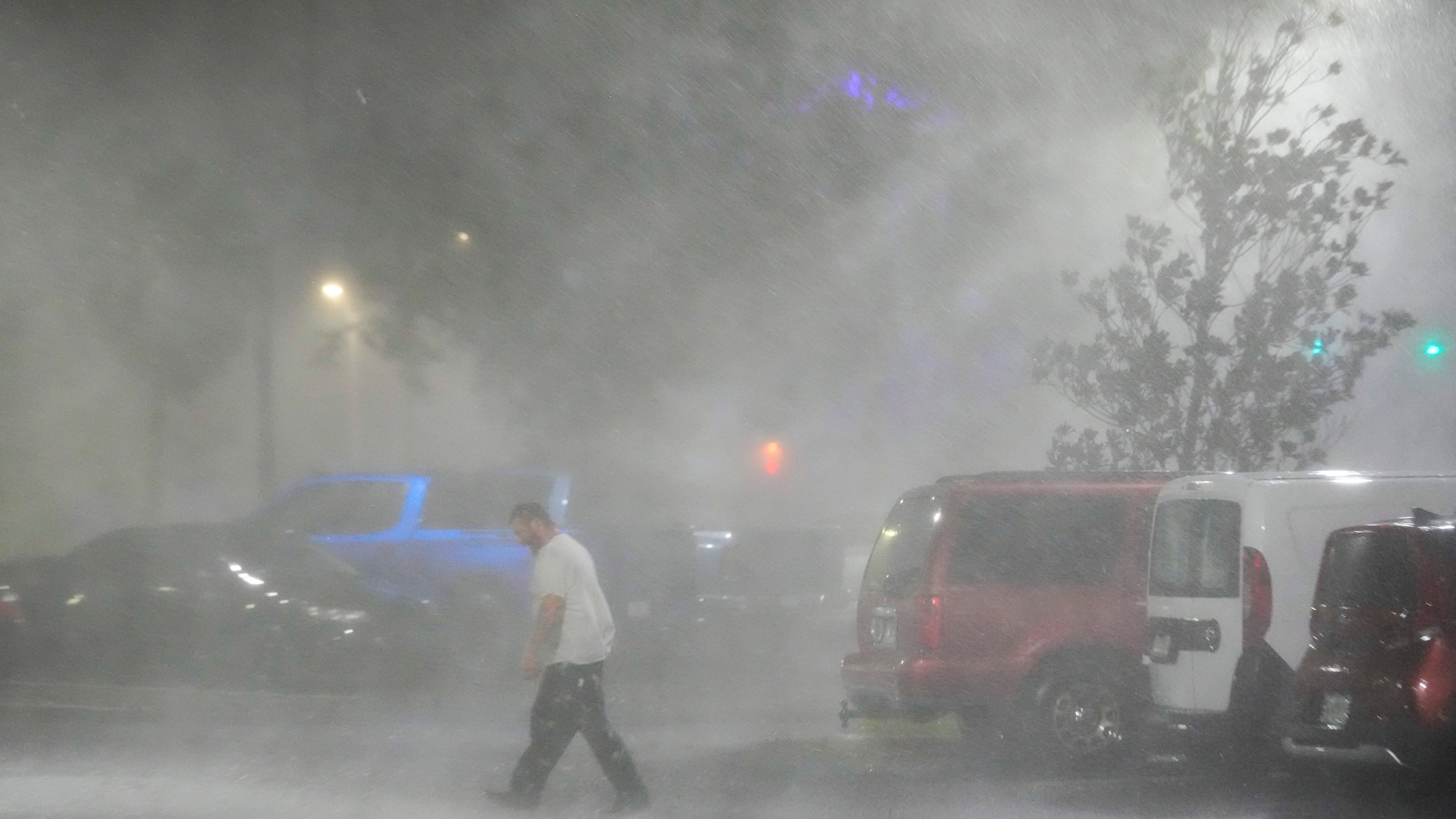 Max Watts, of Buford, Ga., walks in the parking lot to check on a trailer parked outside the hotel where he is riding out Hurricane Milton with coworkers, Wednesday, Oct. 9, 2024, in Tampa, Fla. Watts, who works for a towing company, was deployed with colleagues to Florida to aid in the aftermath of the storm. (AP Photo/Julio Cortez)