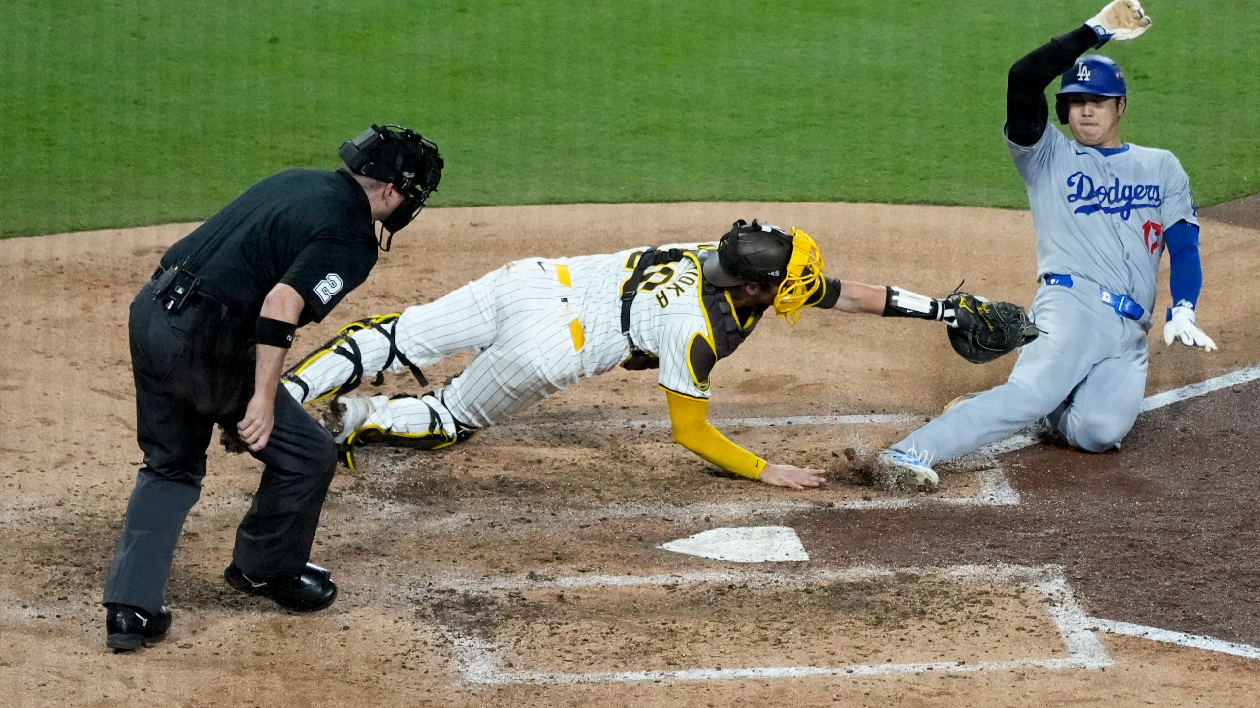 Los Angeles Dodgers' Shohei Ohtani, right, is tagged out at home plate by San Diego Padres catcher Kyle Higashioka after a single by Teoscar Hernández during the fourth inning in Game 4 of a baseball NL Division Series Wednesday, Oct. 9, 2024, in San Diego.(AP Photo/Ashley Landis)