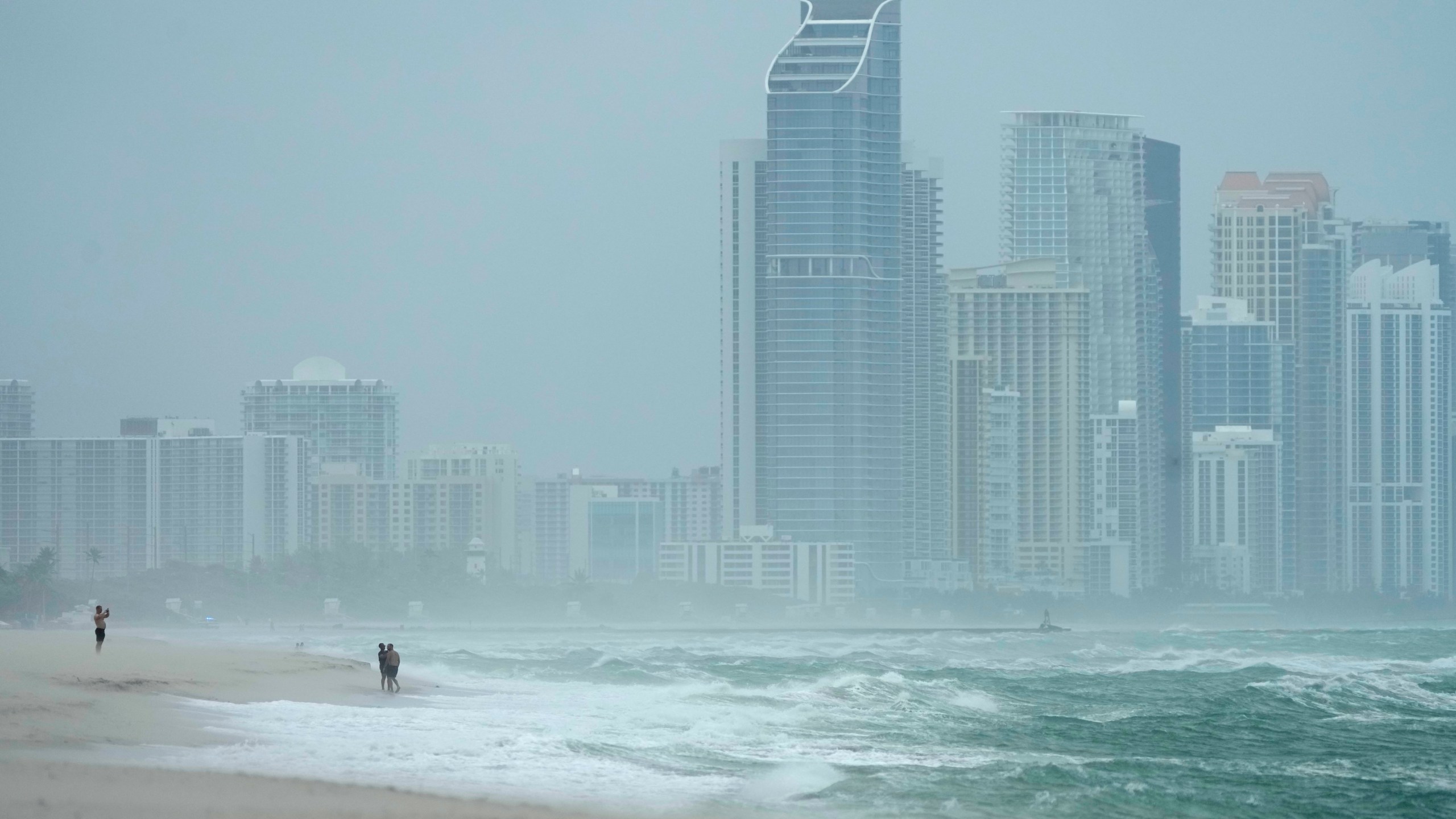 The city of Sunny Isles Beach, Fla., is seen from Surfside, Fla., as the outer bands of Hurricane Milton kick up the sand, Wednesday, Oct. 9, 2024. (AP Photo/Wilfredo Lee)