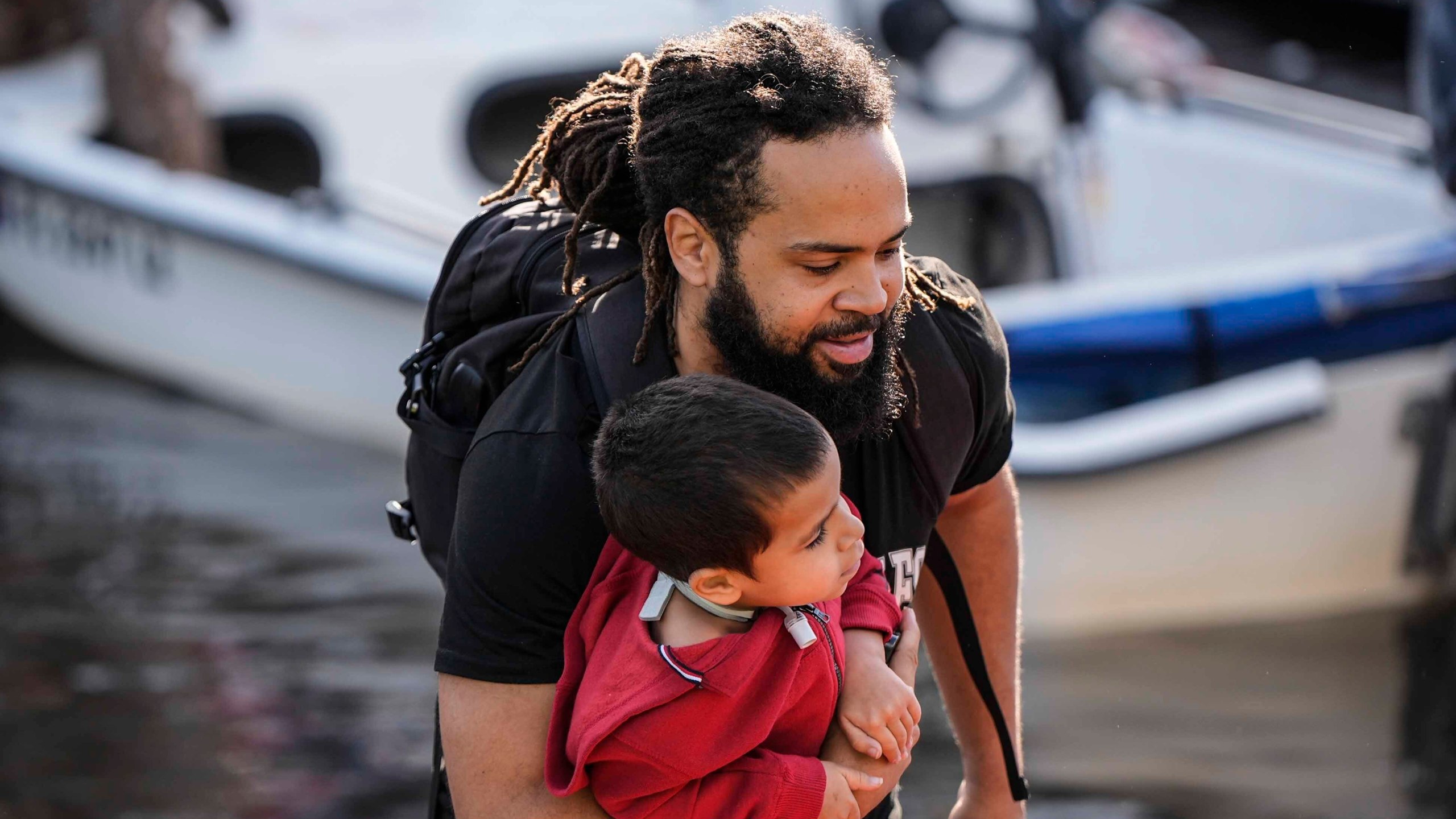 A man and child leave a rescue boat after high flood waters entered their apartment in the aftermath of Hurricane Milton, Thursday, Oct. 10, 2024, in Clearwater, Fla. (AP Photo/Mike Stewart)