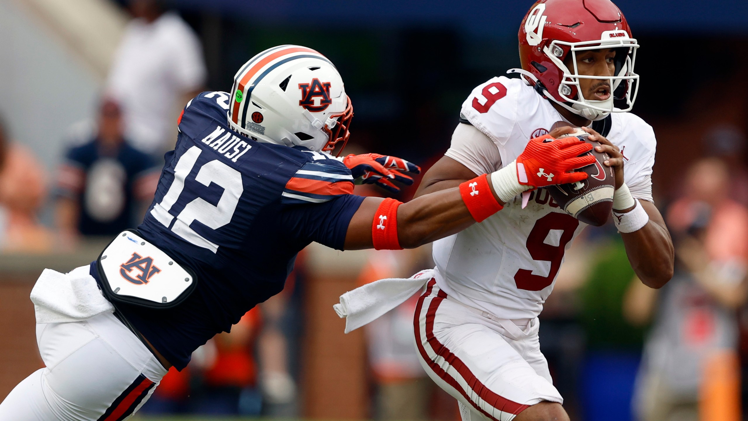 Oklahoma quarterback Michael Hawkins Jr. (9) escapes the pressure from Auburn linebacker Dorian Mausi Jr. (12) as he scrambles from the pocket during the first half of an NCAA college football game, Saturday, Sept. 28, 2024, in Auburn, Ala. (AP Photo/Butch Dill)