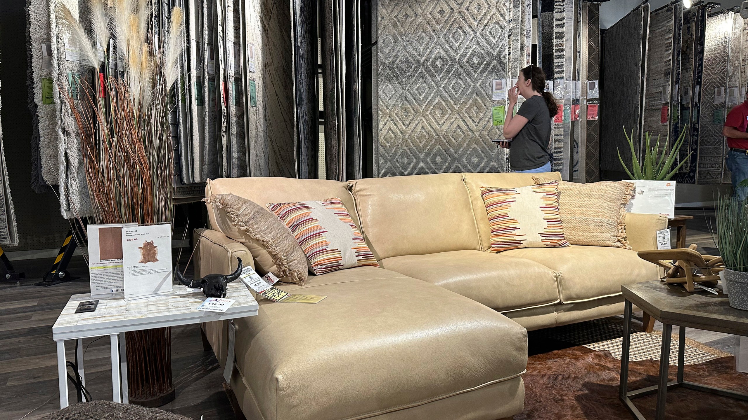 FILE - A shopper considers rug samples near a display of furniture in a store on June 2, 2024, in Lone Tree, Colo. (AP Photo/David Zalubowski, File)