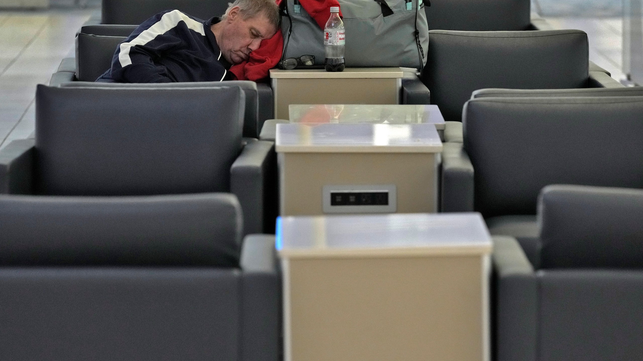 A passenger sleeps at the Tampa International Airport Tuesday, Oct. 8, 2024, in Tampa, Fla., after most flights were canceled due to the possible arrival of Hurricane Milton. (AP Photo/Chris O'Meara)