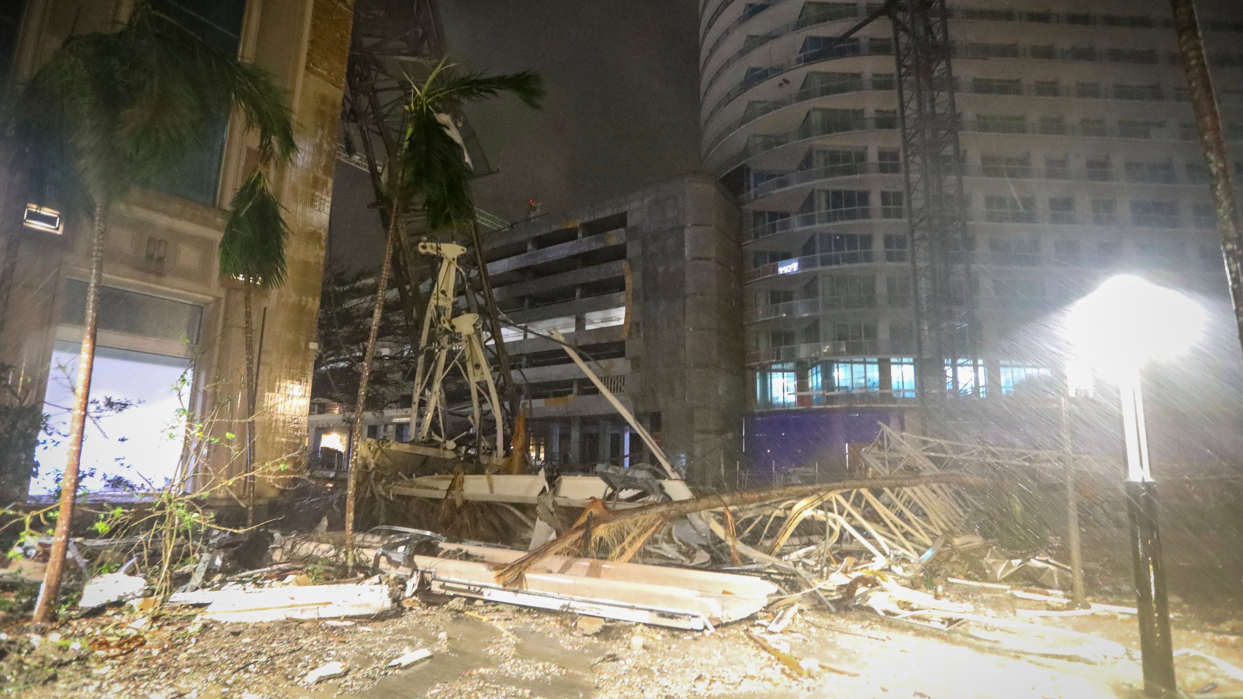 Debris covers the ground near a crane that fell onto a building along 1st Avenue South in St. Petersburg, Fla., as Hurricane Milton's strong winds tore through the area Thursday, Oct. 10, 2024. (Chris Urso/Tampa Bay Times via AP)