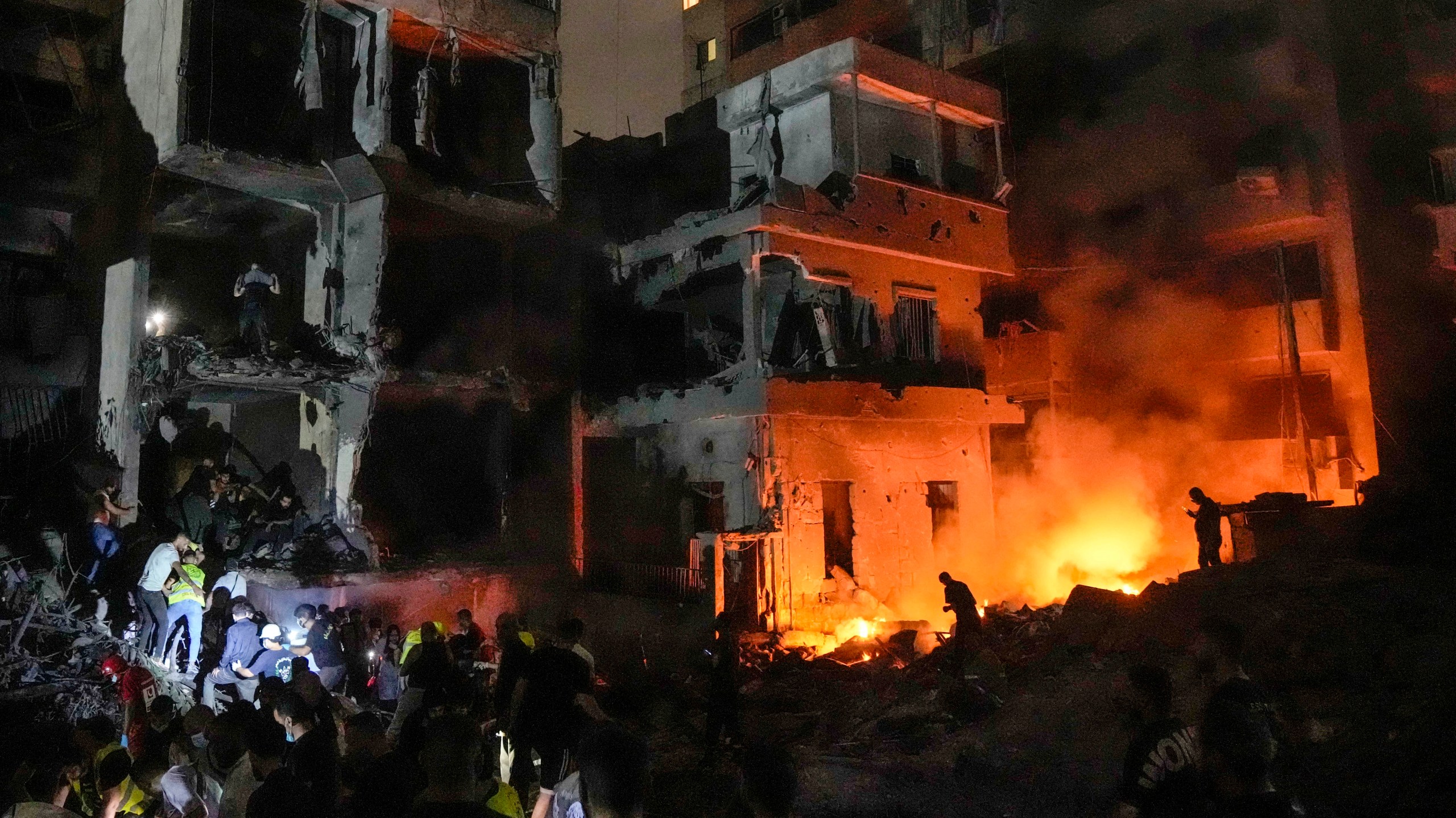 People gather in front of destroyed buildings hit by an Israeli airstrike in central Beirut, Lebanon, Thursday, Oct. 10, 2024. (AP Photo/Bilal Hussein)