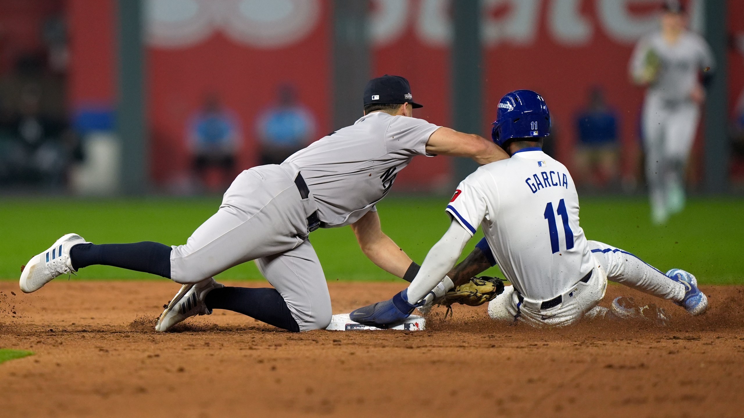 Kansas City Royals' Maikel Garcia, right, is tagged out at second by New York Yankees shortstop Anthony Volpe on a double play during the sixth inning in Game 4 of an American League Division baseball playoff series Thursday, Oct. 10, 2024, in Kansas City, Mo. The Royals' Michael Massey was out at first. (AP Photo/Charlie Riedel)