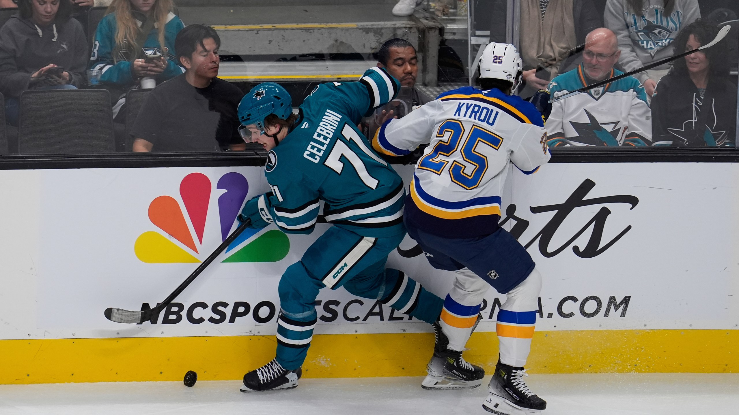 San Jose Sharks center Macklin Celebrini, left, and St. Louis Blues center Jordan Kyrou (25) complete for possession of the puck during the first period of an NHL hockey game Thursday, Oct. 10, 2024, in San Jose, Calif. (AP Photo/Godofredo A. Vásquez)