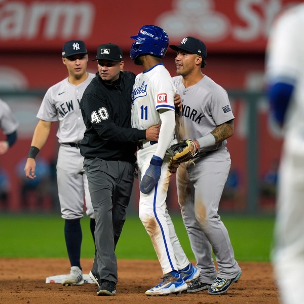 Umpire Roberto Ortiz holds back Kansas City Royals' Maikel Garcia (11) after being tagged out by New York Yankees shortstop Anthony Volpe as the benches empty after a double play during the sixth inning in Game 4 of an American League Division baseball playoff series Thursday, Oct. 10, 2024, in Kansas City, Mo. (AP Photo/Charlie Riedel)