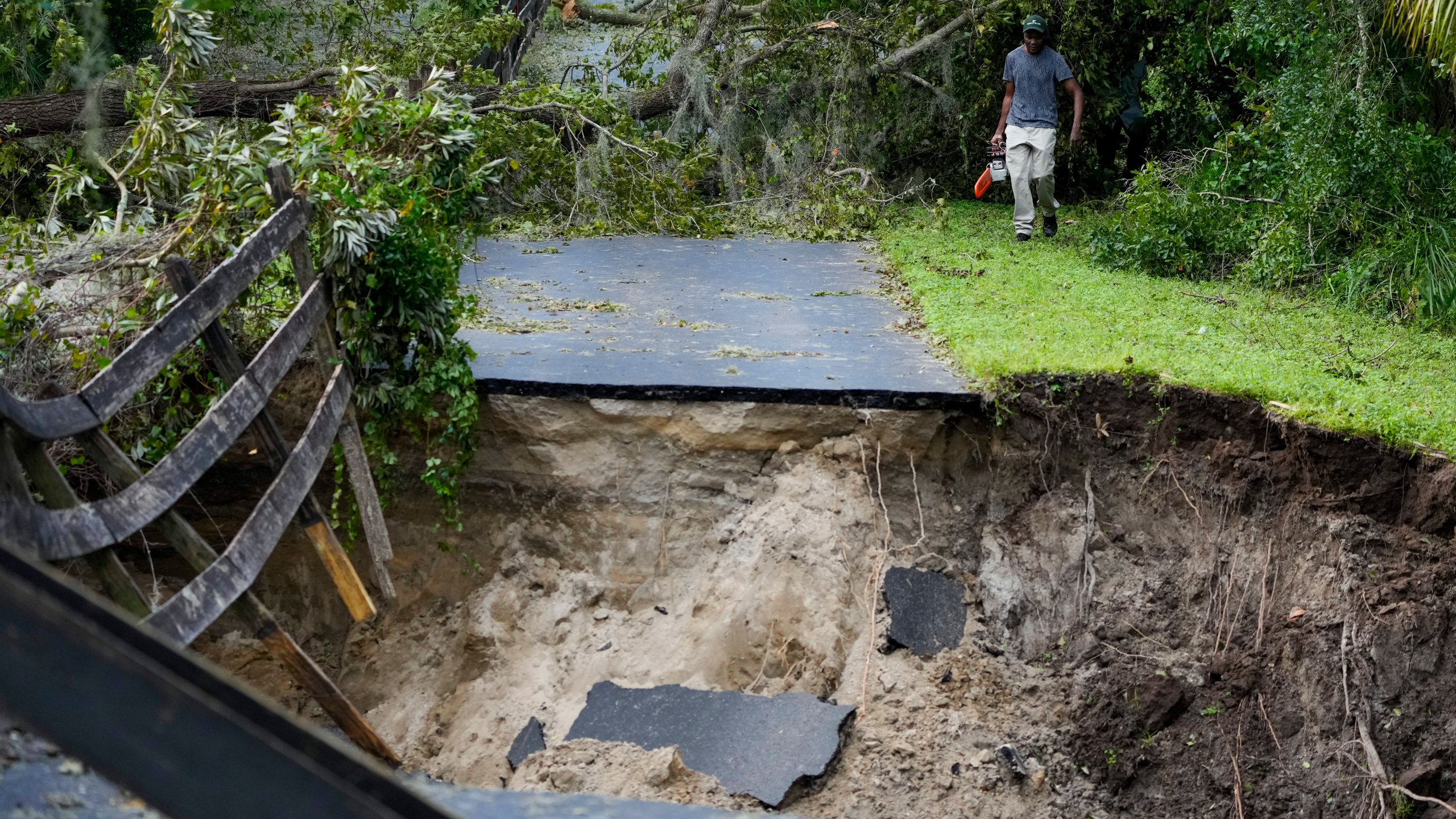 Renel Prophet carries a chainsaw to get it repaired after it broke while cleaning out down trees in his property, which became unaccessible during Hurricane Milton, Friday, Oct. 11, 2024, in Riverview, Fla. (AP Photo/Julio Cortez)