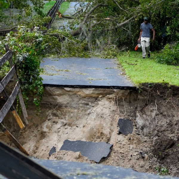 Renel Prophet carries a chainsaw to get it repaired after it broke while cleaning out down trees in his property, which became unaccessible during Hurricane Milton, Friday, Oct. 11, 2024, in Riverview, Fla. (AP Photo/Julio Cortez)