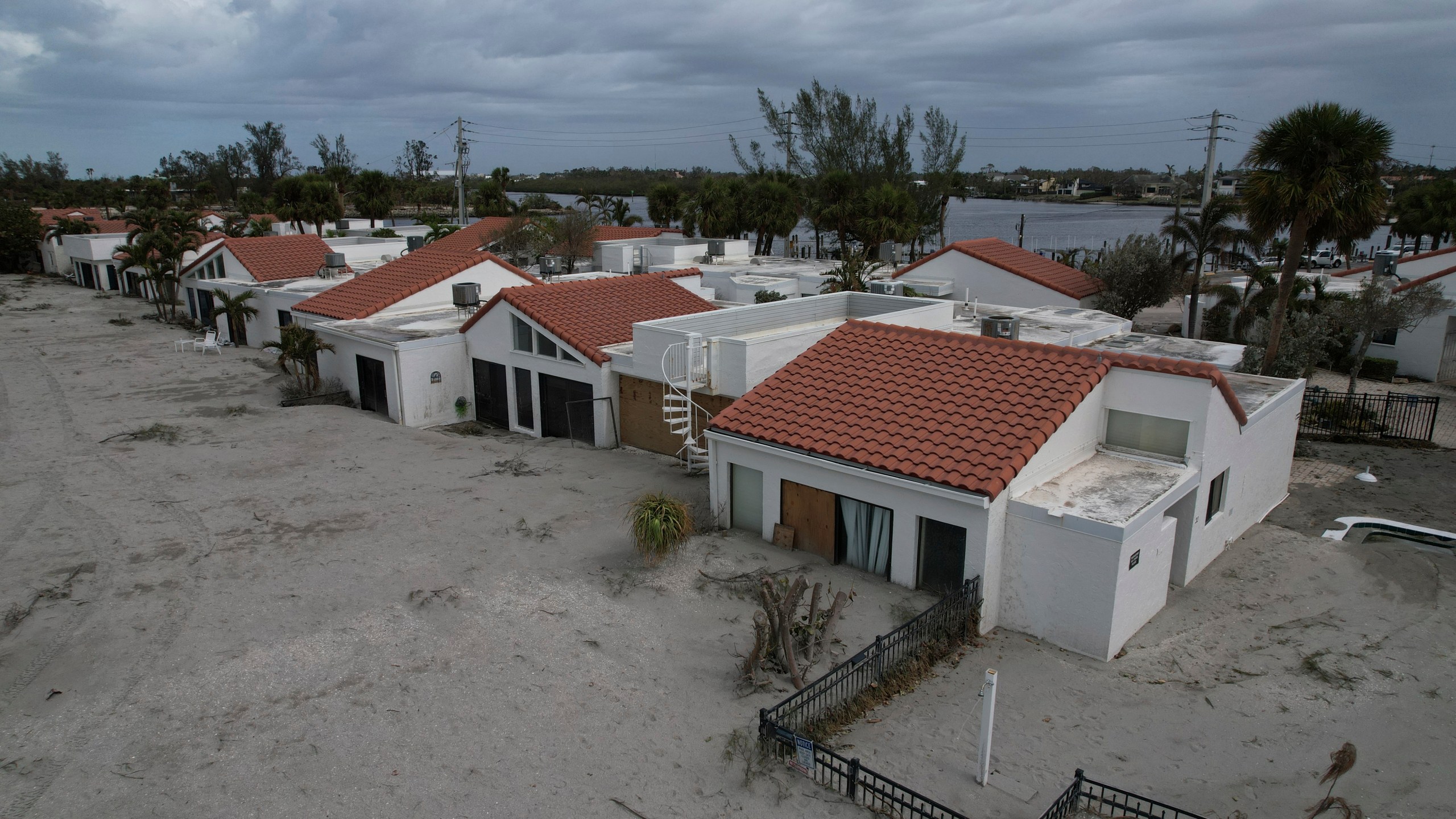 Sand swept by Hurricane Milton reaches half-way up the sliding doors of a beachfront villa, next to a pool deck where the 8 1/2 foot deep pool had disappeared under sand, at Jetty Villas on the island of Venice, Fla., Friday, Oct. 11, 2024. (AP Photo/Rebecca Blackwell)