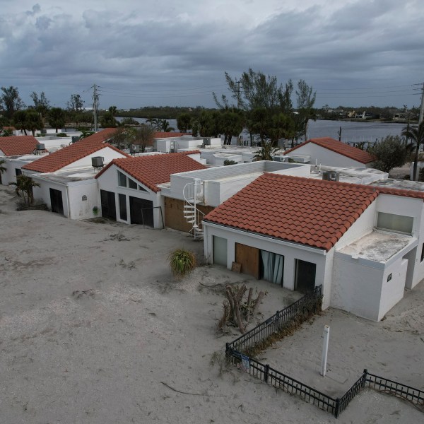 Sand swept by Hurricane Milton reaches half-way up the sliding doors of a beachfront villa, next to a pool deck where the 8 1/2 foot deep pool had disappeared under sand, at Jetty Villas on the island of Venice, Fla., Friday, Oct. 11, 2024. (AP Photo/Rebecca Blackwell)