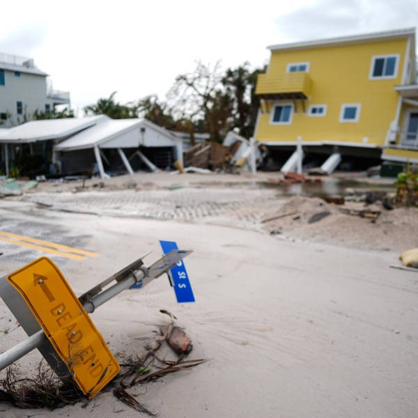 A house sits toppled off its stilts after the passage of Hurricane Milton, alongside an empty lot where a home was swept away by Hurricane Helene, in Bradenton Beach on Anna Maria Island, Fla., Thursday, Oct. 10, 2024. (AP Photo/Rebecca Blackwell)