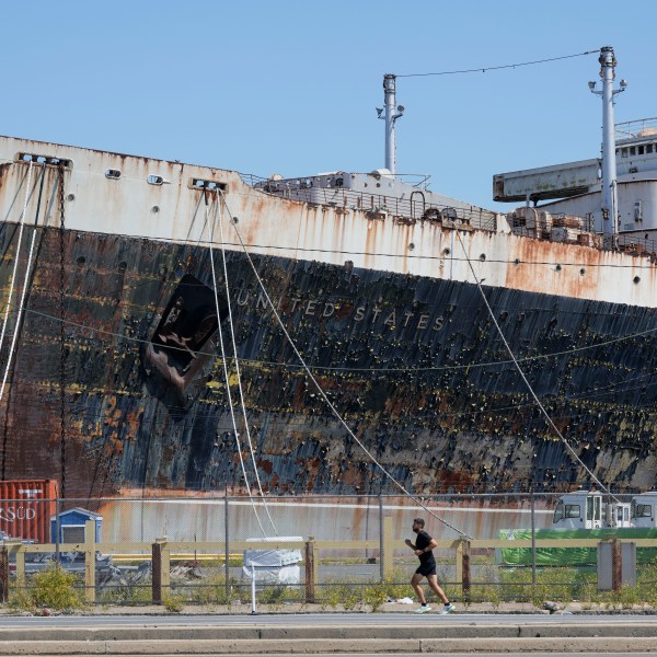 FILE - A person runs past the S.S. United States moored on the Delaware River in Philadelphia, Sept. 4, 2024. (AP Photo/Matt Rourke, File)