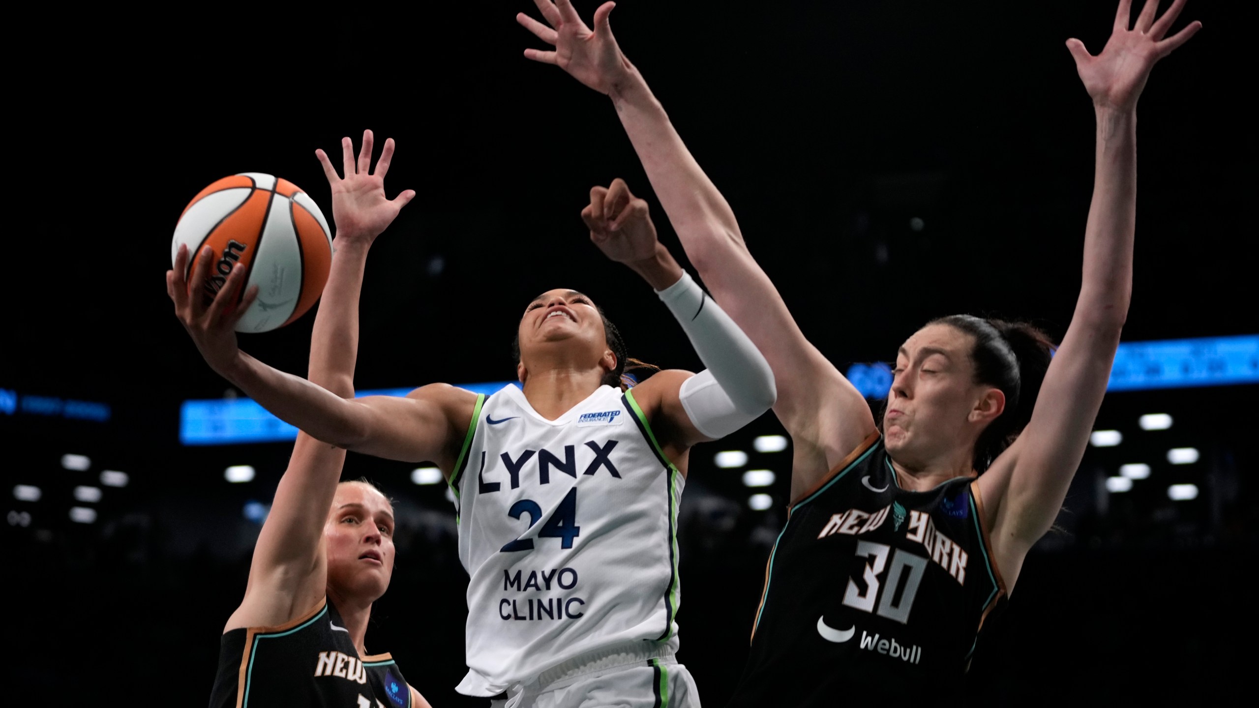 Minnesota Lynx's Napheesa Collier, center, attempts to score against New York Liberty's Leonie Fiebich, left, and Breanna Stewart, right during the second half in Game 1 of a WNBA basketball final playoff series, Thursday, Oct. 10, 2024, in New York. (AP Photo/Pamela Smith)