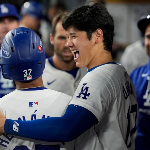 Los Angeles Dodgers' Teoscar Hernández, left, celebrates his solo home run in the dugout with Shohei Ohtani during the seventh inning in Game 5 of a baseball NL Division Series against the San Diego Padres, Friday, Oct. 11, 2024, in Los Angeles. (AP Photo/Ashley Landis)