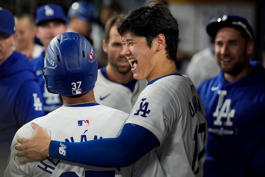 Los Angeles Dodgers' Teoscar Hernández, left, celebrates his solo home run in the dugout with Shohei Ohtani during the seventh inning in Game 5 of a baseball NL Division Series against the San Diego Padres, Friday, Oct. 11, 2024, in Los Angeles. (AP Photo/Ashley Landis)