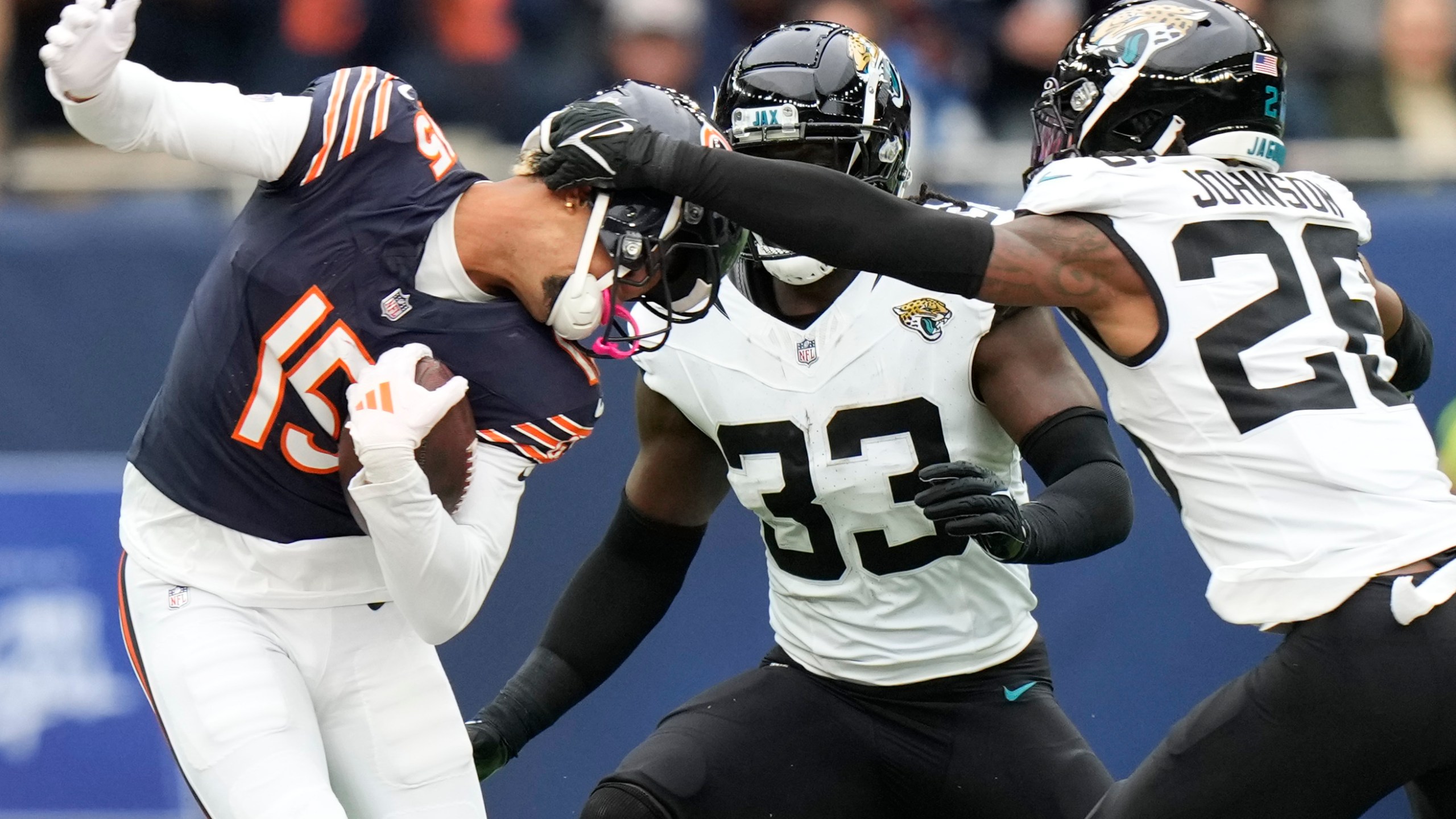 Chicago Bears wide receiver Rome Odunze (15) is tackled by Jacksonville Jaguars linebacker Devin Lloyd (33) and Jaguars safety Antonio Johnson (26) during an NFL football game at the Tottenham Hotspur stadium between the Jacksonville Jaguars and Chicago Bears in London, Sunday, Oct. 13, 2024. (AP Photo/Alastair Grant)